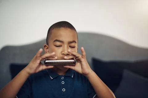 I love playing the harmonica. a young boy playing the harmonica at home. Stock Photos