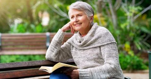I love reading stories. a cheerful elderly woman reading a book by herself Stock Photos