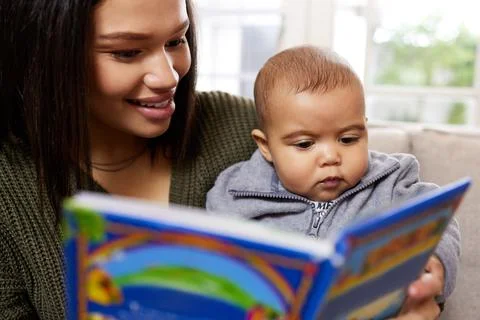 I love these little people. Shot a mother reading a book to her baby at home. Stock Photos