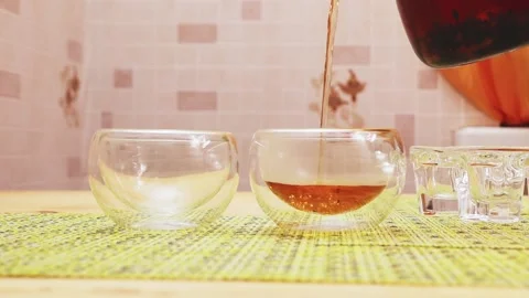 I pour black tea from a transparent glass teapot into a glass mug Stock Footage 229650292