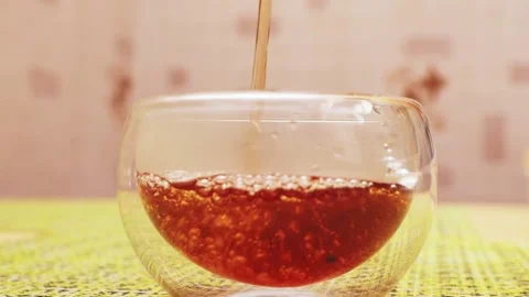 I pour black tea from a transparent glass teapot into a glass mug Stock Footage 229650338