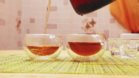 I pour black tea from a transparent glass teapot into a glass mug Stock Footage 229650354