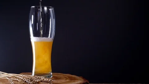 I pour cold light beer into a glass with foam Stock Footage 125374570