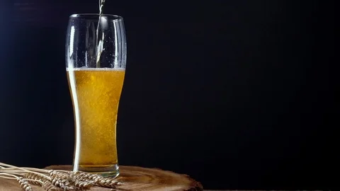 I pour cold light beer into a glass with foam Stock Footage 125374581