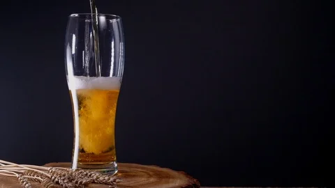 I pour cold light beer into a glass with foam Stock Footage 125374600