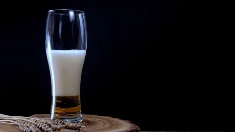 I pour cold light beer into a glass with foam Stock Footage 125374616