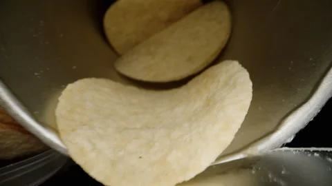 I pour a stack of corn chips from a long can onto the table. Black background. D Stock Footage 260933769