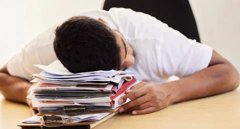I rather nap than work. an unrecognisable man asleep on a stack of paperwork Stock Photos