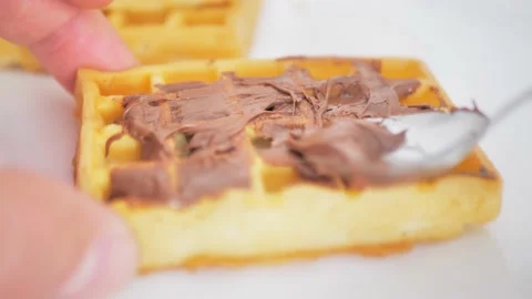 I spread chocolate on a Wiener waffle with a spoon while the camera passes Stock Footage 223386121