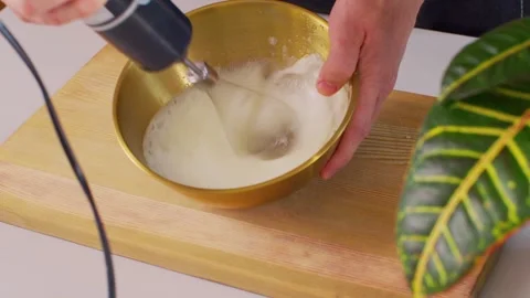 I start beating the egg whites with a mixer in a golden bowl. 스톡 동영상 312720385
