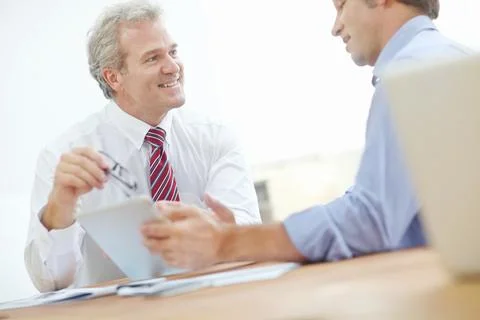 I like these recent developments. Two male business associates sitting at a desk Stock Photos