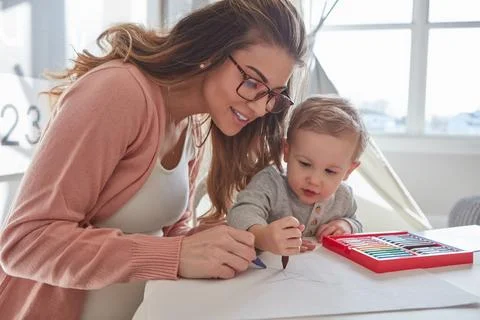 I think scribbling is his new favourite activity. a woman and her young son Stock Photos