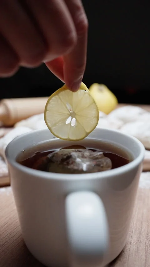 I throw a slice of lemon into tea against the background of pies, slow motion.  Video stock 221467714