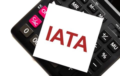 IATA text, written on a note that lies on a calculator and a white background Stock Photos
