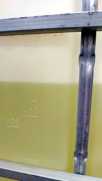 IBC containers filled with liquid show measurement markers in industrial se.. Stock Photos
