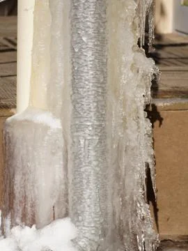 Ice and icicles on a drainpipe. Drainpipe covered with ice and icicles. Stock Photos