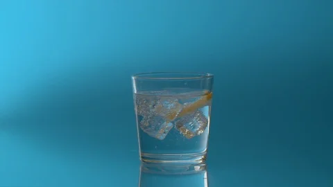 Ice and a slice of lemon spinning in a glass Stock Footage 123994026