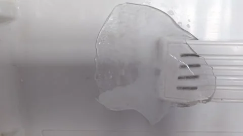 Ice block melting on a refrigerator shelf, revealing water droplets and a Stock Footage 334324369