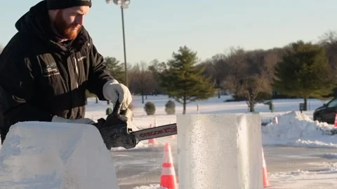 Ice carver cutting block of ice with electric chainsaw in competition Stock Footage 147354492