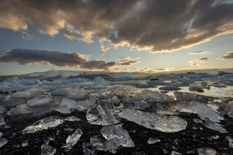 Ice chunks washed ashore at the edge of Jokulsarlon glacier lagoon at sunset Stock Photos