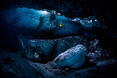 Ice climber abseiling into massive cavern in ice cave Stock Photos