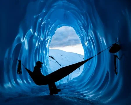 Ice climber resting in hammock inside a deep blue ice cave in the Matanuska G Stock Photos
