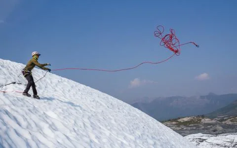 Ice climber tossing a rope down a slope on the Matanuska Glacier in Alaska. Stock Photos
