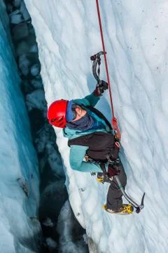 Ice climbing guide down inside a deep crevasse filled with water. Stock Photos