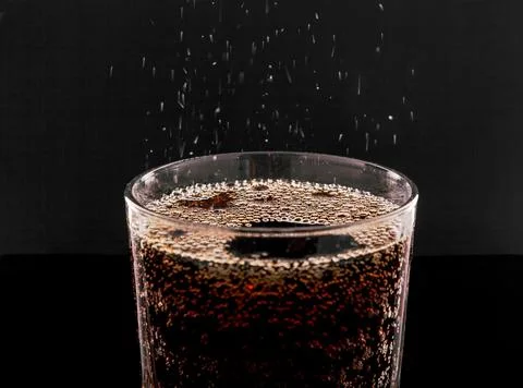 Ice Cola with splashes and bubbles. Drink in a transparent glass on a black b Stock Photos