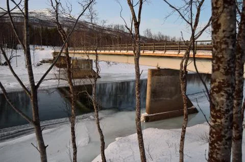 Ice cold river stream running underneath old weathered metal car bridge Stock Photos