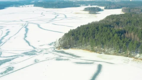 Ice covered lake surrounded by forest, winter snow, aerial drone view Stock Footage 302906850