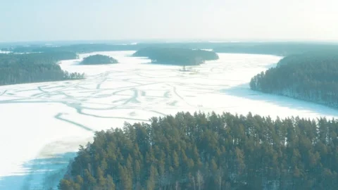 Ice covered lake surrounded by forest, winter snow, aerial drone view Stock-Footage 302906928