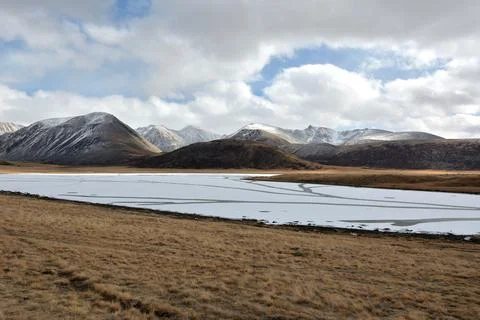 The ice-covered surface of a large mountain lake with clearings lies in the.. Stock Photos
