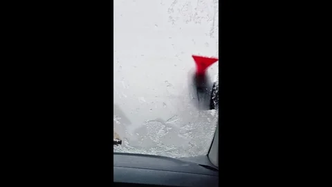 Ice-covered windshield being cleared in cold winter conditions vertical video Stock Footage 325994511