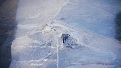 Ice cracks around rock in winter pond, 4k Stock Footage 166121945