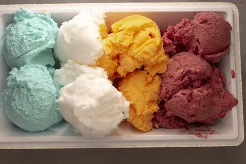 Ice cream arranged in a plastic container on a surface, refreshing top-down. Fotos Stock