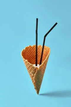 Ice cream cone with black drinking straws and milk shake on bright blue Stock Photos