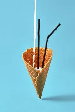 Ice cream cone with black drinking straws and milk shake on bright blue Stock Photos