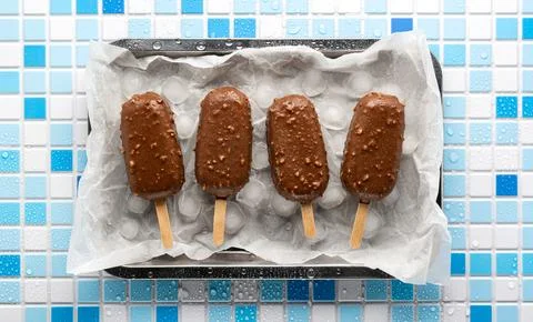 Ice cream eskimo flat lay. Top view of a chocolate-glazed popsicle with crushed Stock Photos