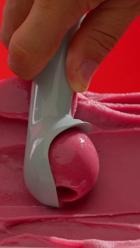 Ice cream scooping. Scoop pink sorbet on red background. Vertical close-up Stock Footage 313419152