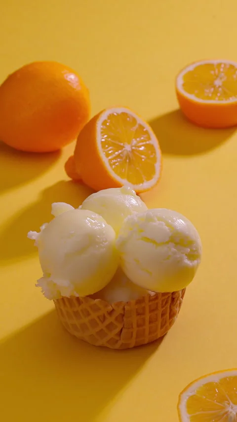 Ice cream scoops stacked into waffle cone surrounded by fresh lemons. Vertical Stock Footage 313161042
