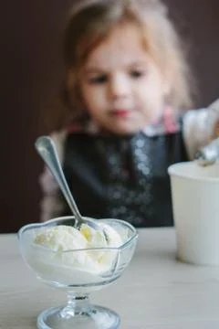 Ice cream on table and little girl on background. Stock Photos