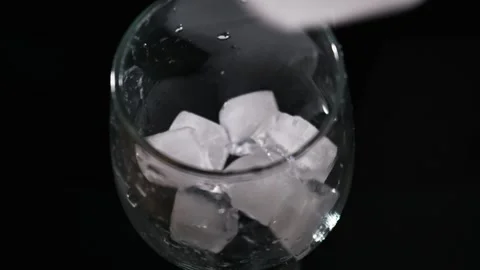 Ice Cube Being Dropped Into Clear Glass of Water on Black Background Stock Footage 339366072