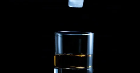 Ice cube being dropped in the glass of whiskey in slow motion Stock Footage 71221900
