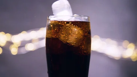 Ice cube drop into glass ful of cola, super slow motion close up shot. Stock Footage 128700868