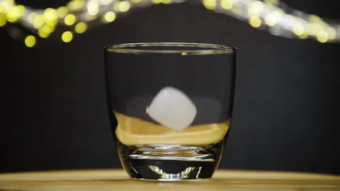 Ice cube dropped into empty glass and rotate Stock Footage 128425270