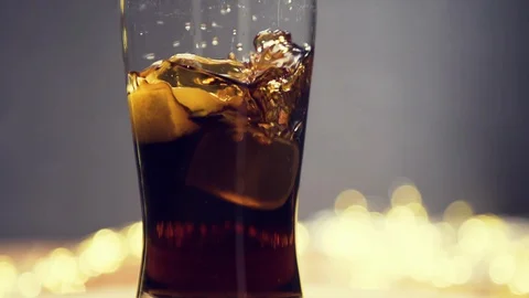 Ice cube dropped into glass full of Cola Stock Footage 128924063
