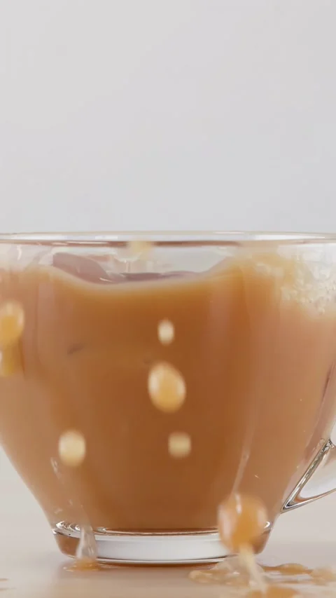 Ice Cube Dropping into Glass Cup of Milk Tea with Splash Stock Footage 342087339