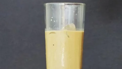 Ice cube dropping into a glass of iced coffee Vidéo 347630372
