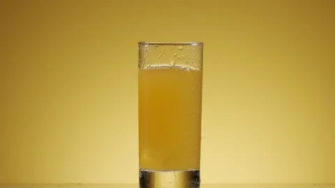 Ice cube dropping in a glass of orange juice in slow motion Stock Footage 342740861